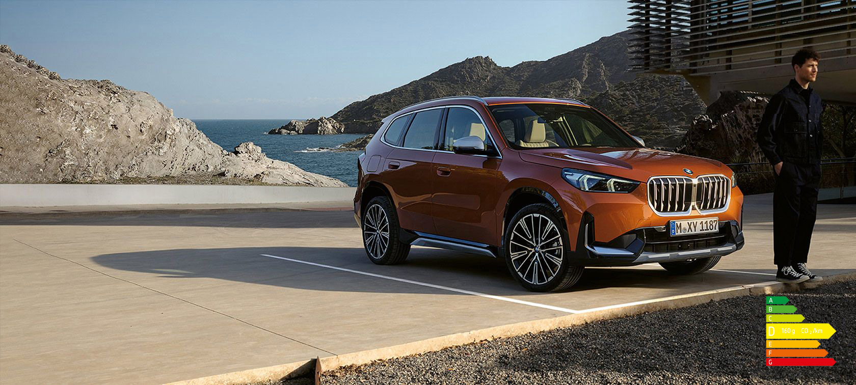 BMW X1 U11 xLine Utah orange metallic, vue de trois quarts avant sur route de campagne